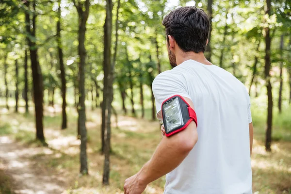 Athletic young sportsman with handband running in forest