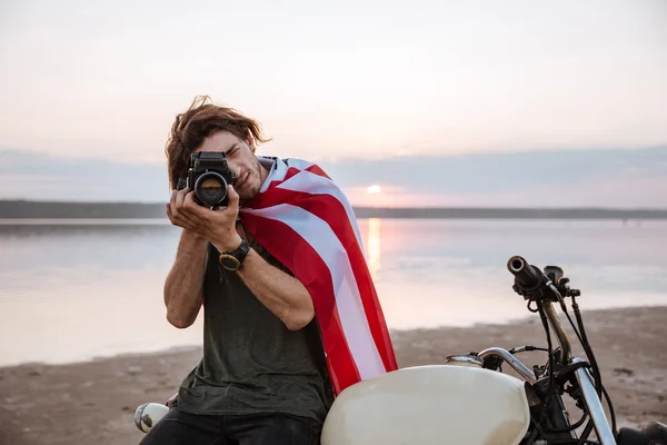 Man making photo with camera while sitting on his motocycle