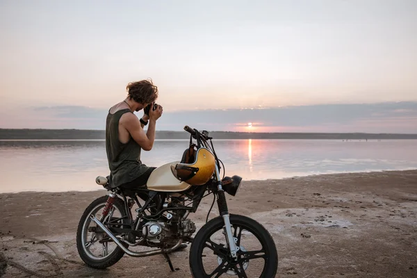 Man making photo with camera while sitting on his motocycle