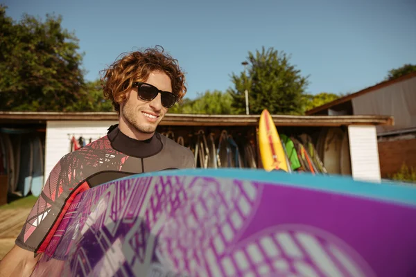 Young handsome curly man going to surf