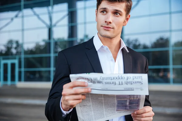 Portrait of a handsome businessman holding newspaper outdoors