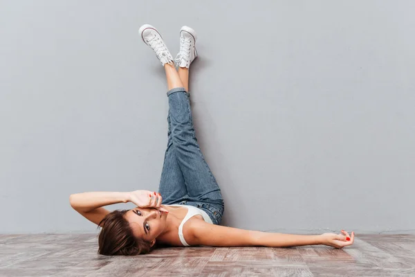 Smiling beautiful woman lying on the floor with raised legs