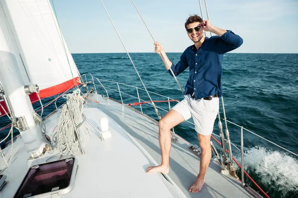 Man looking forward and smiling while standing on the yacht