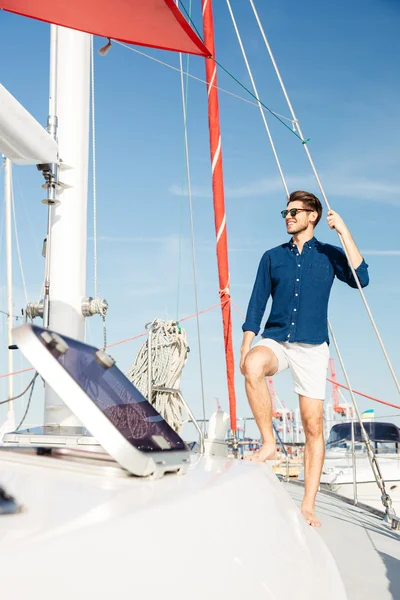 Young stylish sailor man standing on the yacht