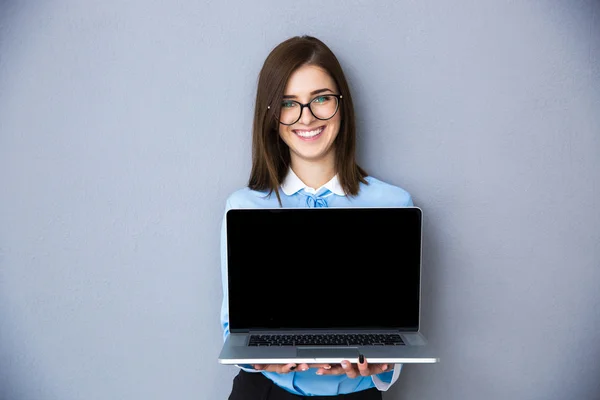 Happy businesswoman showing blank laptop screen