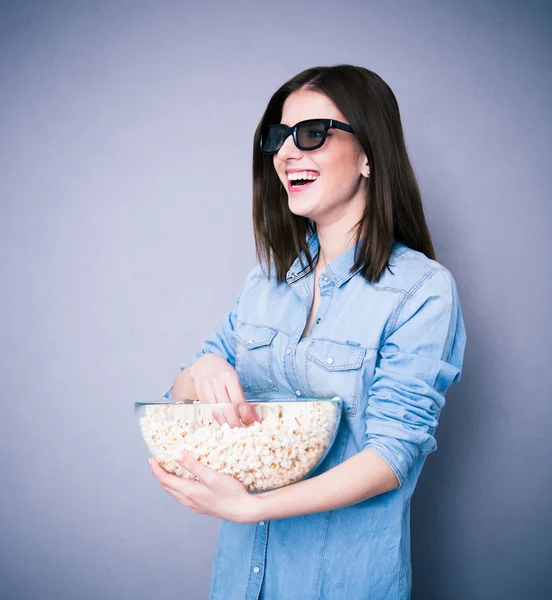 Lauhging woman in cinema glasses holding bowl with popcorn