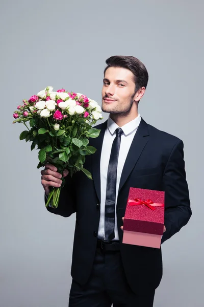 Businessman holding flowers and gift box