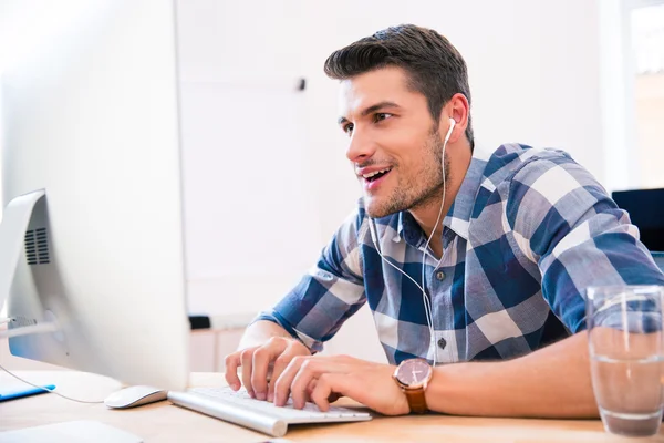 Happy businessman in headphones using PC