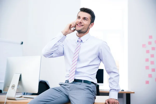 Happy businessman talking on the phone in office