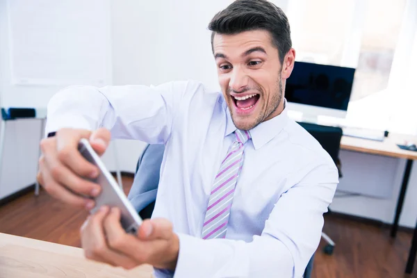 Businessman playing in game on the phone in office