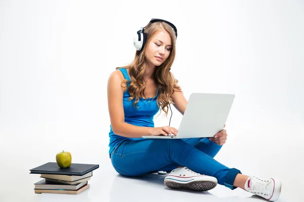 Girl using laptop in headphones on the floor