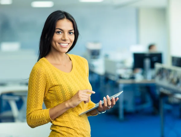 Businesswoman standing with tablet computer in office