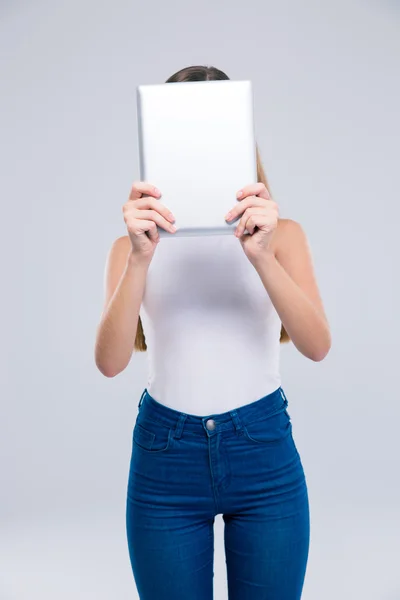 Female teenager covering her face with tablet computer