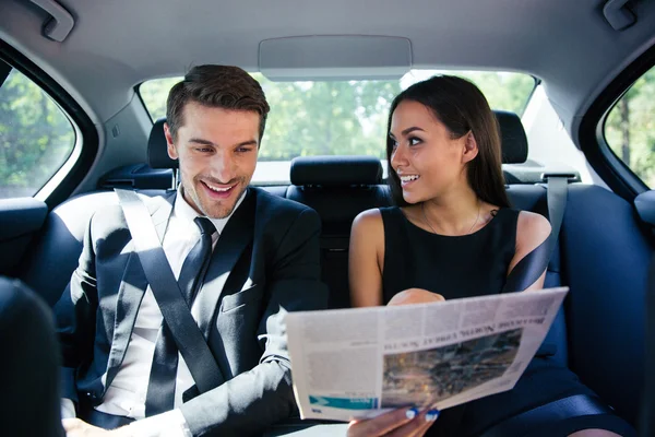 Couple reading newspaper in car