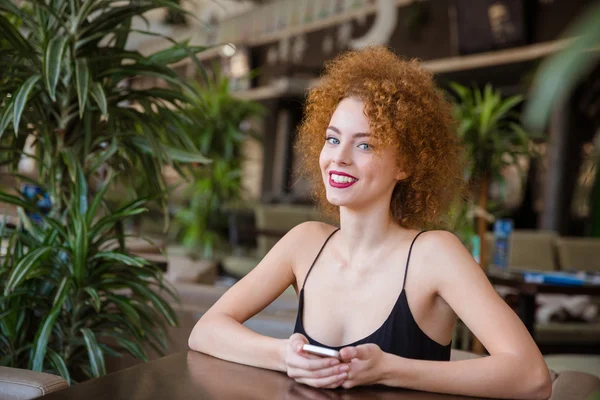 Smiling redhead woman sitting at the table in restaurant