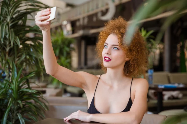 Woman taking selfie photo on smartphone in restaurant