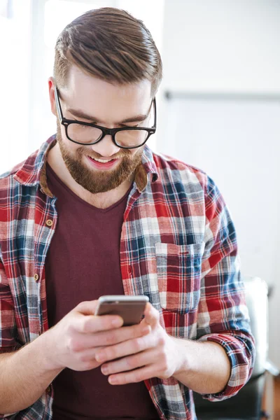 Smiling handsome bearded man using mobile phone