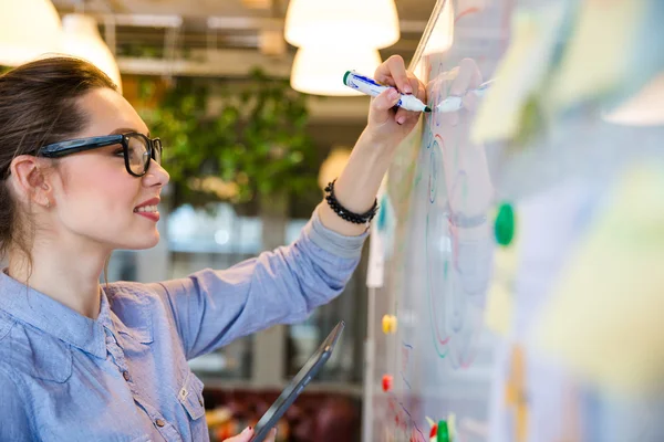 Businesswoman writing something on whiteboard