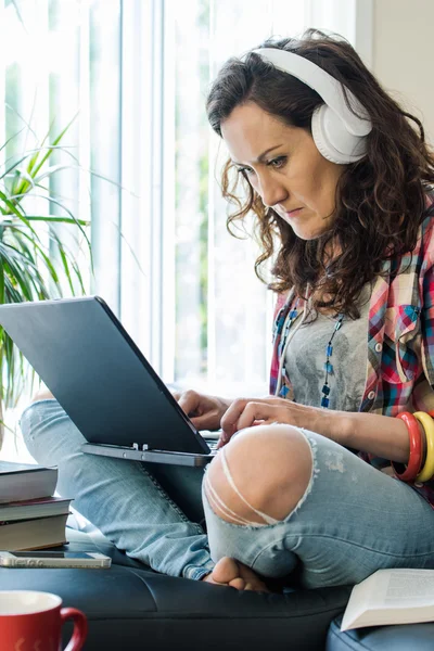 Female with headphones work on laptop