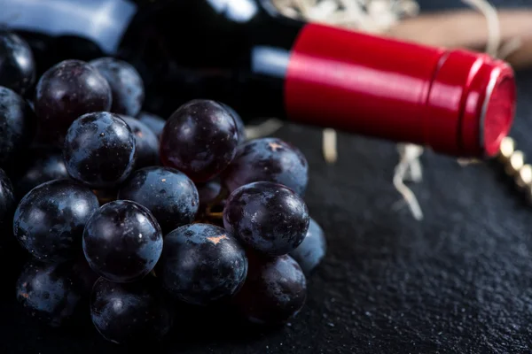 Red wine bottle with grapes and corkscrew