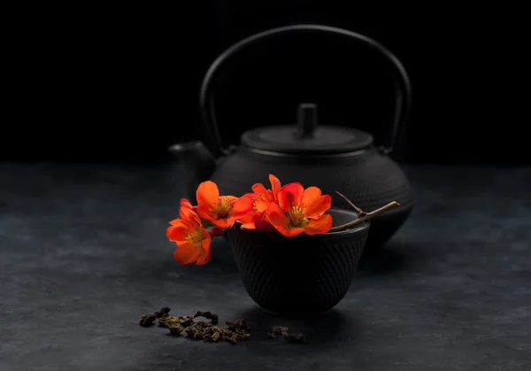 Green tea and flowers. Asian tea set. Cast-iron pot and cup.