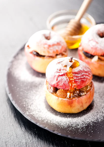 Baked apple stuffed with honey, raisins and nuts on dark background