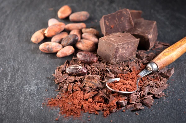 Chocolate, cocoa beans and cocoa powder on a stone background