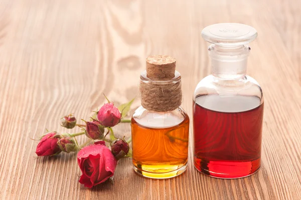 Rose essential oil and rose flowers on a white background