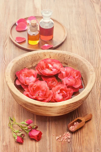 Rose essential oil and rose flowers on a white background