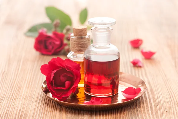 Rose essential oil and rose flowers on a white background