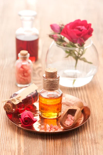 Rose essential oil and rose flowers on a white background