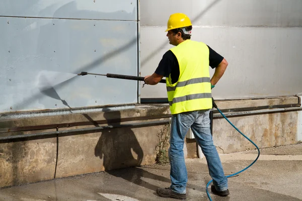 Worker in hard hat pressure washing