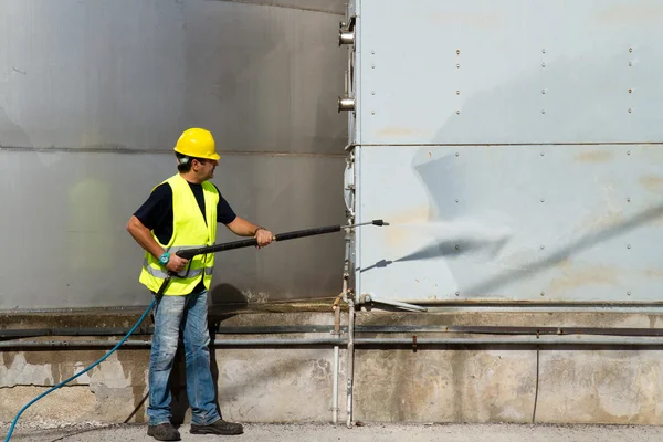 Worker in hard hat pressure washing