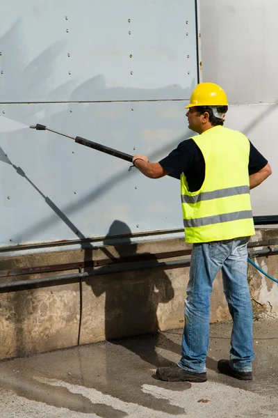 Worker in hard hat pressure washing