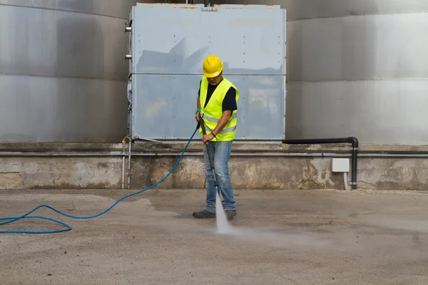 Worker in hard hat pressure washing