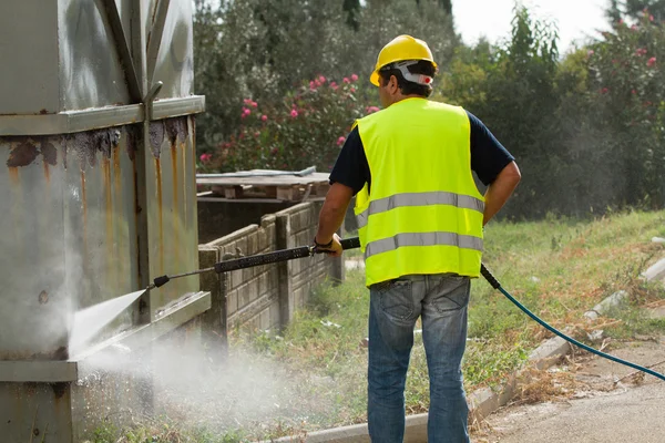 Worker in hard hat pressure washing