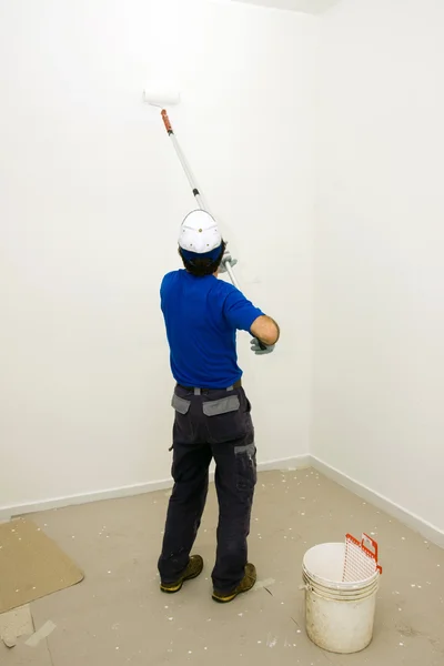 Worker paints the wall with an anchor roller