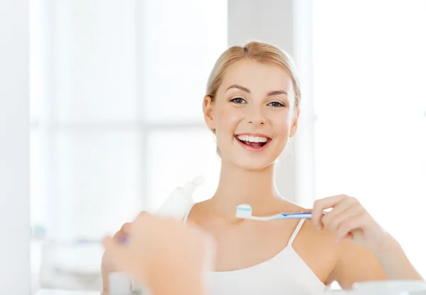 Woman with toothbrush cleaning teeth at bathroom