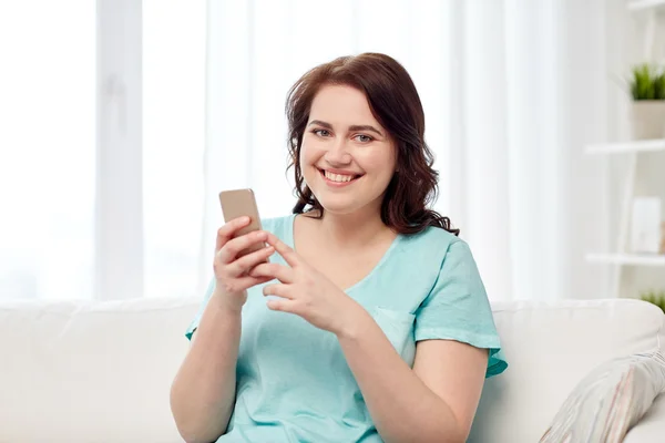 Happy plus size woman with smartphone at home
