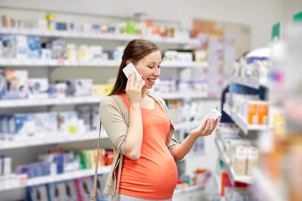 Happy pregnant woman with smartphone at pharmacy