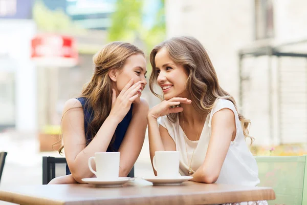 Young women drinking coffee and talking at cafe