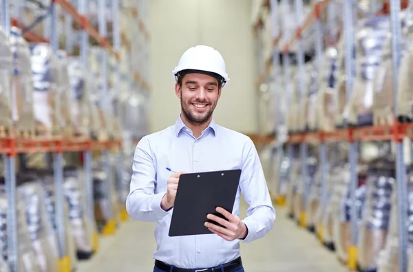 Happy businessman with clipboard at warehouse