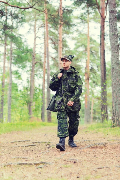 Young soldier or hunter with gun in forest