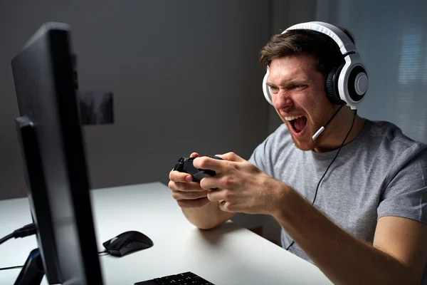 Man in headset playing computer video game at home