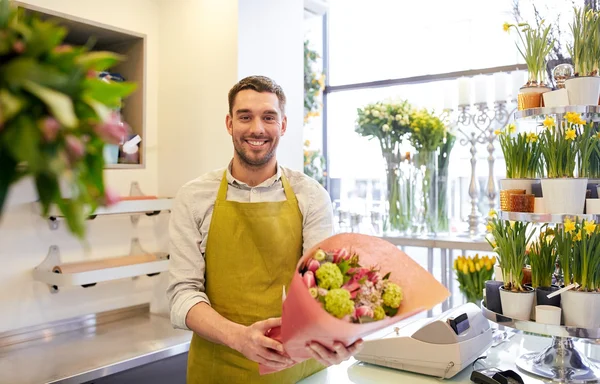 Smiling florist man making bunch at flower shop