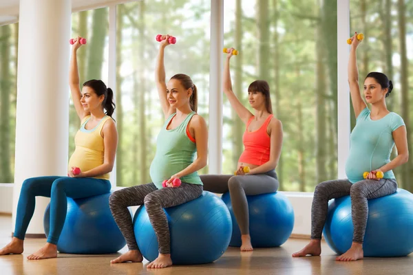 Happy pregnant women exercising on fitball in gym