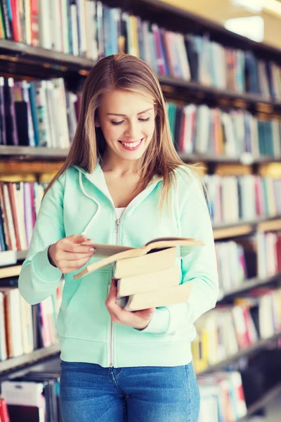 Happy student girl or woman with book in library