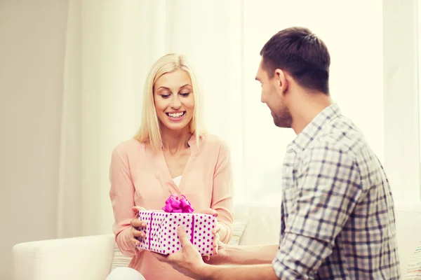 Happy man giving woman gift box at home