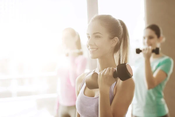 Group of happy women with dumbbells in gym