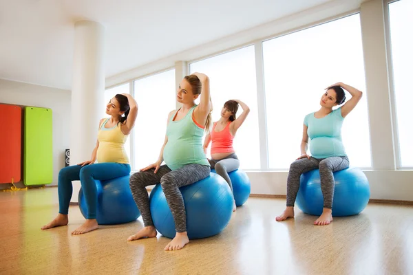Happy pregnant women exercising on fitball in gym